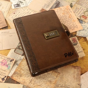 Puede incluir: Un diario de cuero marrón con un candado de combinación y un diseño floral en relieve. El diario tiene la palabra "PAW" escrita en la portada.