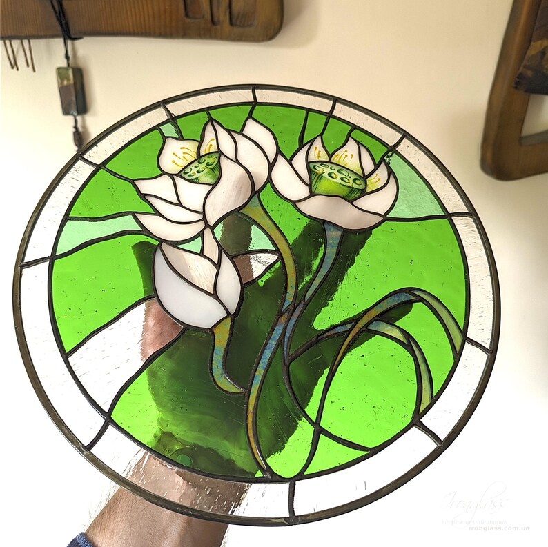 Full view of the round stained glass panel with White lilies, held in a craftsman's hand, against a light studio background, showcasing the vibrant green pastel wall art and the overall design for a perfect Mothers day gift.