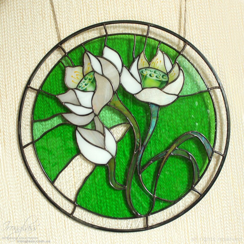 Close-up of the round stained glass panel featuring White lilies, hanging against a neutral textured background, emphasizing the fine soldering work and the master's tiffany glass art technique.