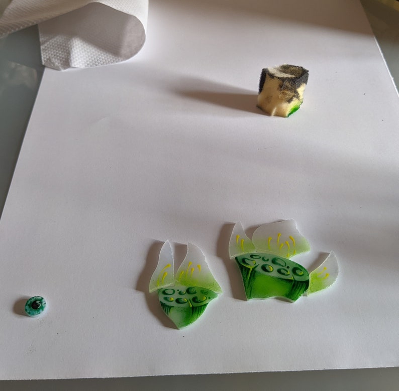 In-progress shot showing the hand-painted high-quality American glass pieces used for the lily stamens and seed pods on a white background, highlighting the authentic tiffany glass art technique.