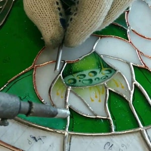 Stained glass soldering. A close-up of the soldering of a fragment of a stained glass hanging panel with lilies.