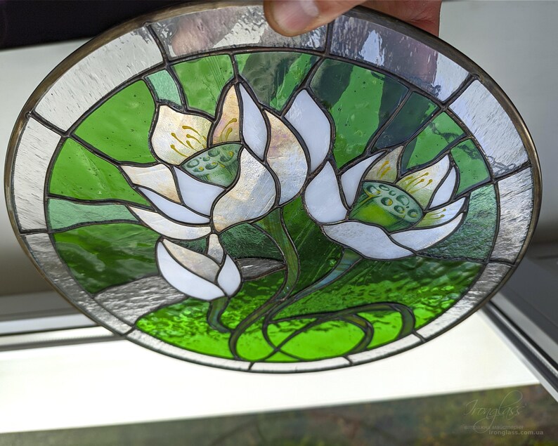 Hand-held close-up of the round stained glass panel, clearly showing the craftsmanship of the Tiffany glass art technique and the included natural eco-linen thread for easy display as a windows hangings.
