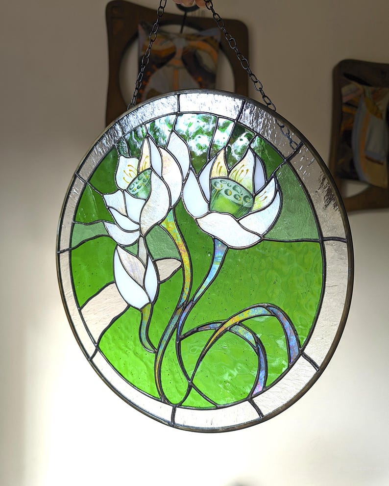 Round window wall hanging featuring White lilies, showcasing the glossy edge glass and the bright green background as a stunning flower suncatcher piece of decor in a contemporary interior setting.