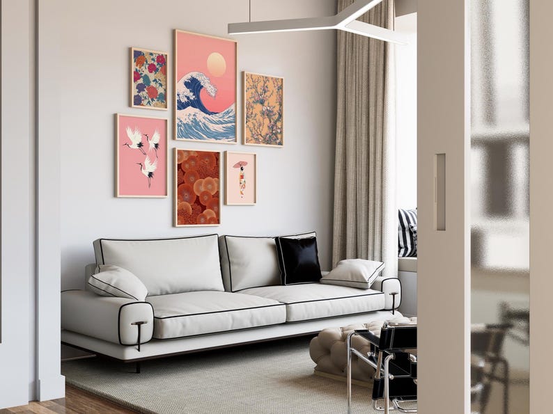 May include: A modern living room featuring a white sofa with black trim, a collection of framed art prints, and a neutral color palette. The art includes a wave, cranes, and floral designs. A black pillow and a light gray rug complete the scene.