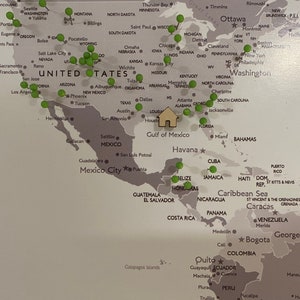 May include: A world map with green push pins marking locations across the globe. The map is printed on a light gray background with dark gray lines and text. The map includes North America, South America, Europe, Africa, Asia, and Australia. The push pins are clustered in the United States, Mexico, and Central America.