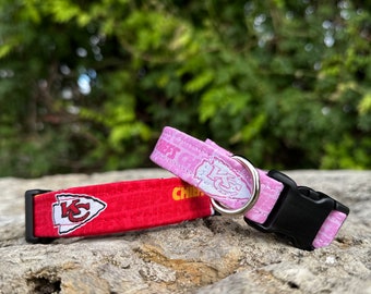 May include: Two dog collars, one red with a Kansas City Chiefs logo and the other pink with a white design. Both collars have black buckles.