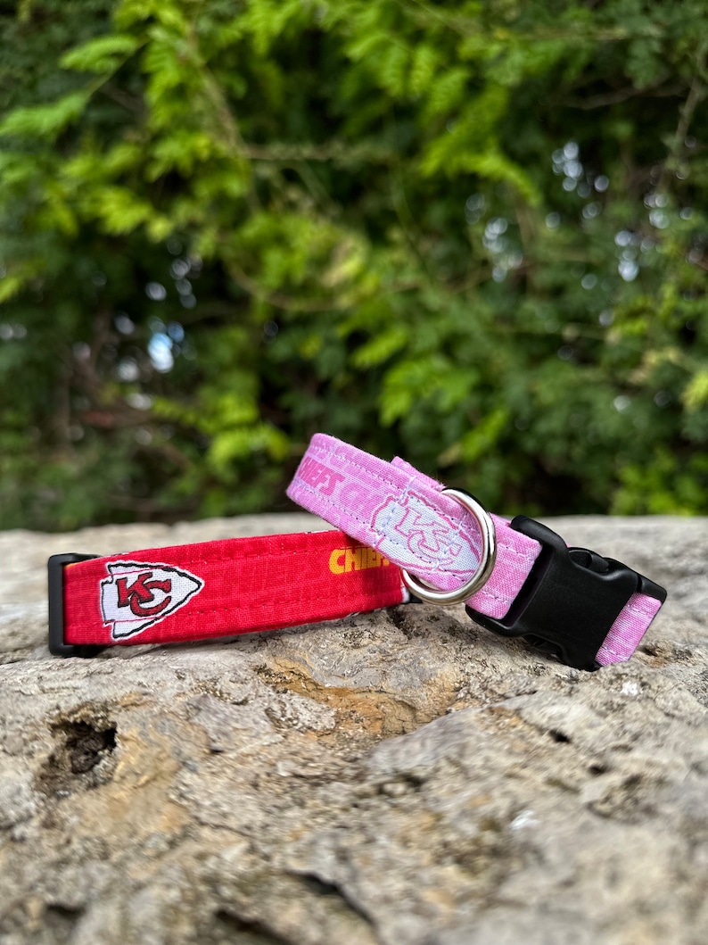 Puede incluir: Dos collares para perros, uno rojo con el logotipo de los Kansas City Chiefs y el otro rosa con un dise&ntilde;o blanco. Ambos collares tienen hebillas negras.