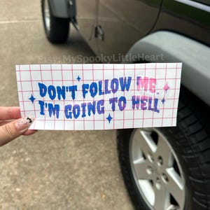 May include: A rectangular white vinyl sticker featuring a red grid pattern and blue and purple gradient text that reads "DON'T FOLLOW ME. I'M GOING TO HELL" with small blue four-pointed star icons scattered across the surface of the sticker.
