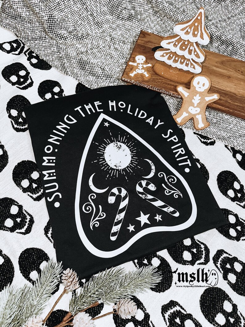 May include: Black t-shirt with a white graphic of a Ouija board with candy canes and the text "Summoning the Holiday Spirit."