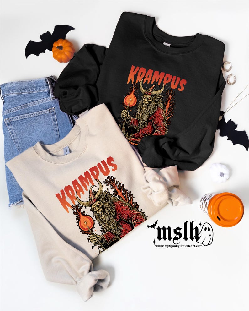 May include: Two cream and black long-sleeved sweatshirts with a graphic print of a red and black creature with horns and a beard. The text "Krampus" is printed in red on both sweatshirts.