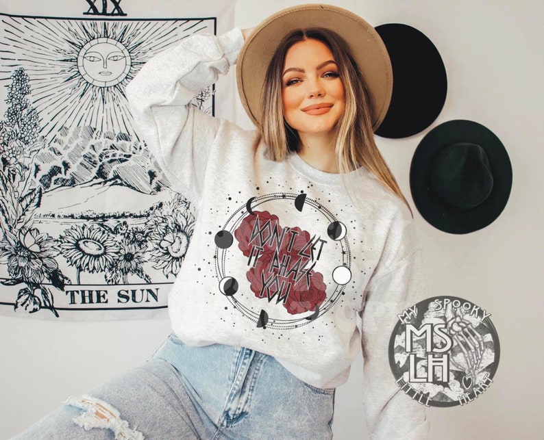 May include: A gray sweatshirt with a graphic design featuring a red rose, a crescent moon, and the text "Don't let it all phase you".
