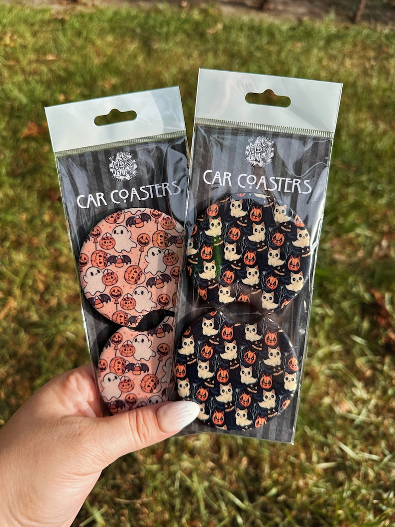 May include: Two sets of Halloween-themed car coasters. Each set includes four coasters with different designs featuring ghosts, pumpkins, and cats. The coasters are round and have a white background with colorful designs.