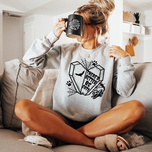 May include: A gray sweatshirt with a black graphic print of a coffin with a bat and the text "There'd Better Be Cats".