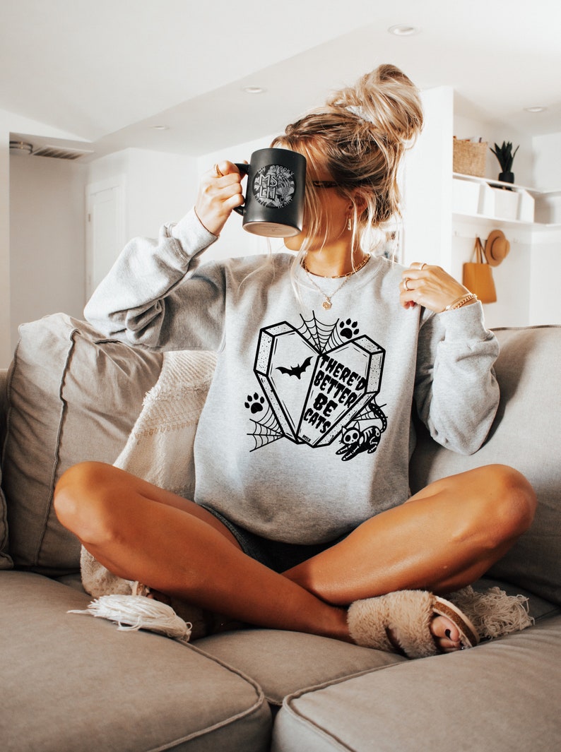 May include: A gray sweatshirt with a black graphic print of a coffin with a bat and the text "There'd Better Be Cats".