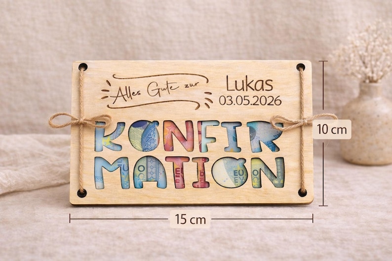 May include: A wooden plaque with the word "KONFIRMATION" cut out, filled with colorful currency. The plaque is 15 cm wide and 10 cm tall, with the text "Alles Gute zur Lukas 03.05.2026" engraved on top. Twine is used for hanging.