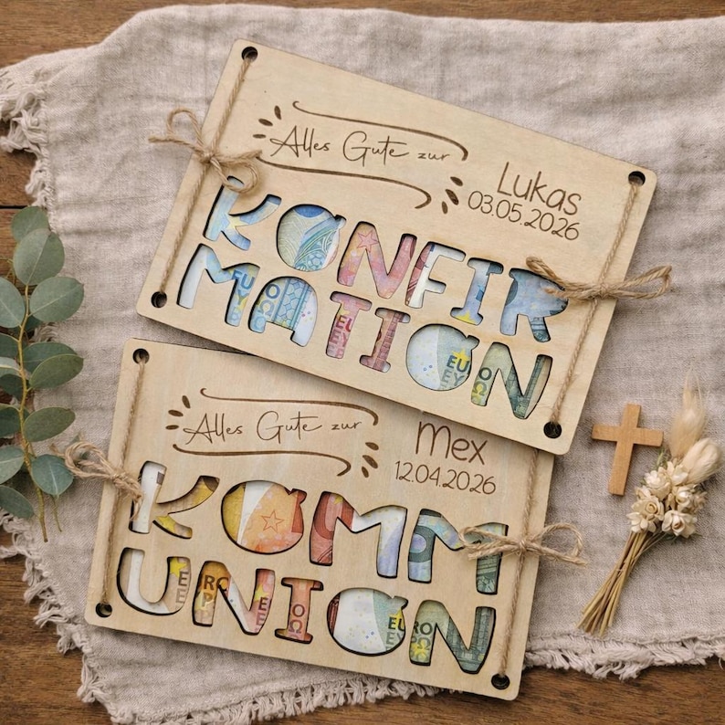 May include: Two wooden gift card holders with cut-out letters spelling "KONFIRMATION" and "KOMMUNION", filled with colorful currency. The top holder has the text "Alles Gute zur Lukas 03.05.2026". The bottom holder has the text "Alles Gute zur Mex 12.04.2026".