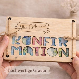 May include: A wooden gift card with the word "KONFIRMATION" cut out, revealing colorful money. The card has the text "Alles Gute zur" engraved at the top and is tied with twine. The phrase "hochwertige Gravur" is also visible.