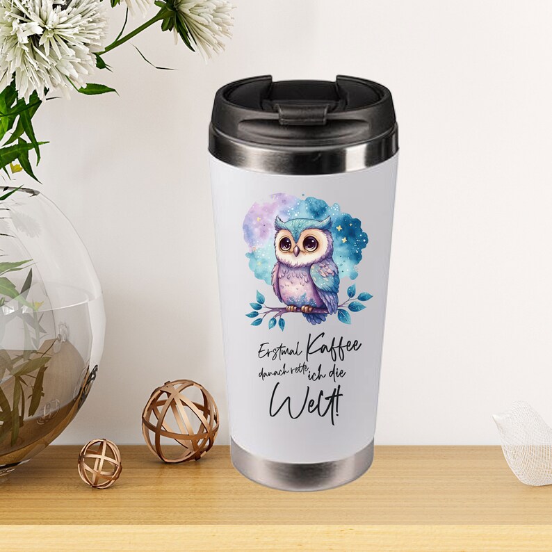 May include: A stainless steel travel mug with a black lid. The mug features a watercolour illustration of a blue and purple owl perched on a branch with a starry background. The text on the mug reads "Erstmal Kaffee, danach rette ich die Welt!"