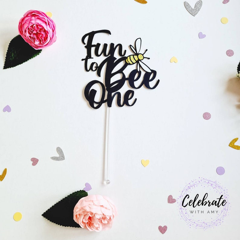 May include: Black acrylic cake topper with the text "Fun to Bee One" and a yellow and black bee illustration.