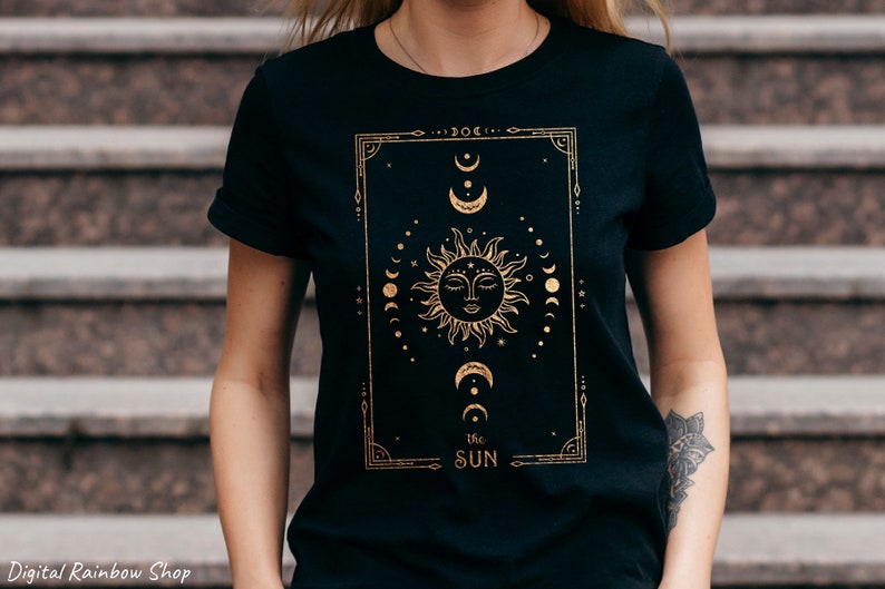 May include: Black t-shirt with a gold foil design of a sun and moon with the text "The Sun" underneath.