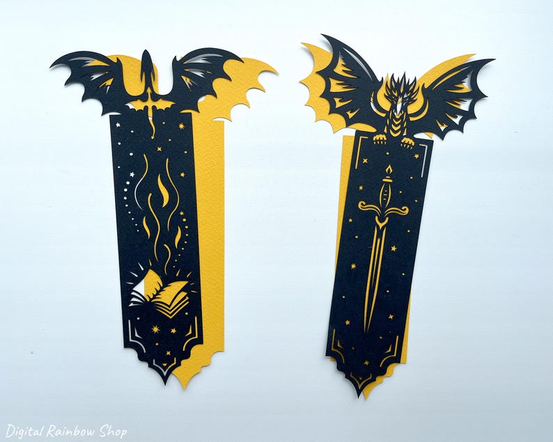 May include: Two fantasy-themed bookmarks with dragon and sword designs. The bookmarks are black and yellow, with intricate cut-out details. One features a dragon with a sword, the other a dragon with a book and flames. Ideal for book lovers.