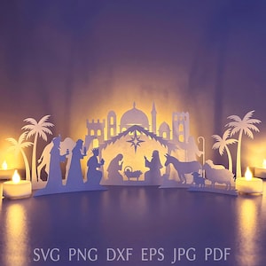 Peut inclure: Une crèche en papier blanc découpé, avec des silhouettes de personnages, de bâtiments et de palmiers. La scène est éclairée par l'arrière, créant une lueur chaleureuse. Le texte en bas indique "SVG PNG DXF EPS JPG PDF".