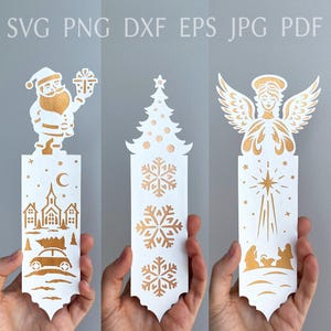 Pode incluir: Três recortes de papel brancos e dourados com tema natalino. Um apresenta o Papai Noel, uma igreja e um carro com uma árvore de Natal. Outro tem uma árvore de Natal e flocos de neve. O último retrata um anjo e uma cena de natividade.