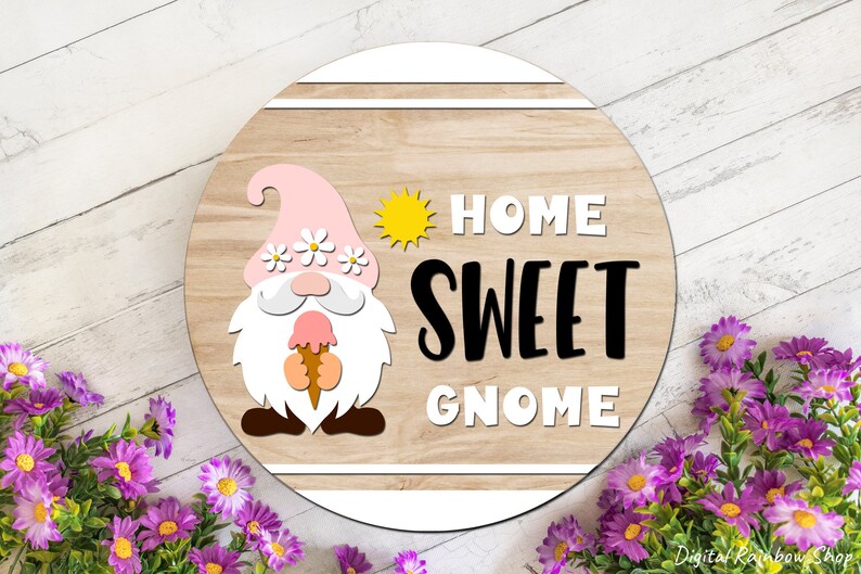 Puede incluir: Un letrero redondo de madera con un gnomo rosa sosteniendo un cono de helado. El letrero dice "Home Sweet Gnome" con un gr&aacute;fico de sol amarillo.