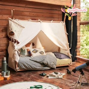 May include: A white canvas teepee tent for kids with a wooden frame. The teepee has a blue and white checkered bedding and pillows with embroidered fish designs. The teepee is set up in a wooden room with a wooden floor.