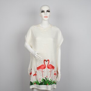 May include: White hooded beach cover-up with a flamingo print. The print features pink flamingos with black dots and green leaves.