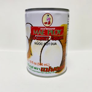 May include: A white can of Mae Ploy Coconut Cream featuring a woman in a pink dress and a coconut on the front. The can is labelled "Coconut Cream" and "Nước Cốt Dừa" in Thai and Vietnamese. The can contains 560 millilitres (19 fluid ounces).