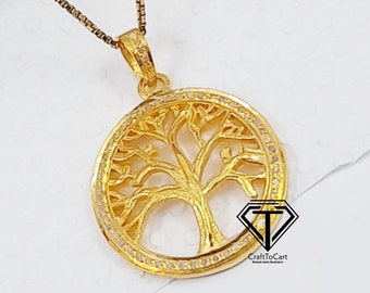 May include: A gold-tone necklace with a tree of life pendant. The pendant is round and features a detailed tree design with a circle of small stones around the edge. The necklace is on a white background.