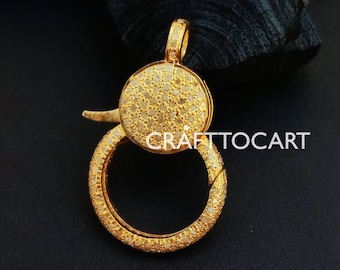 May include: Gold-toned clasp with a round, pave-set design. The clasp is made of metal and features a circle of small, clear stones.