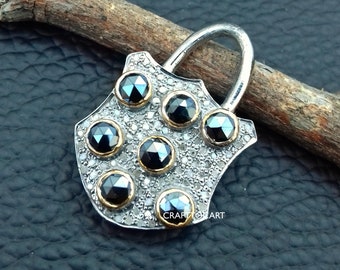 May include: A silver pendant shaped like a shield with a gold trim and seven black diamonds set in the center. The pendant has a loop at the top for attaching a chain.