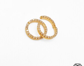 May include: Two gold hoop earrings with a circle of clear cubic zirconia stones around the edge.