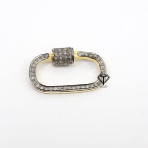 Puede incluir: Un cierre rectangular de color plateado y dorado con un cierre cil&iacute;ndrico, ambos incrustados con peque&ntilde;os diamantes blancos.