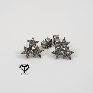 Pu&ograve; includere: Un paio di orecchini a stella in argento con piccoli diamanti trasparenti e marroni. Gli orecchini sono montati su un perno in argento con chiusura a farfalla.