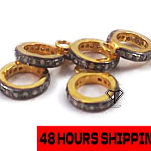 Puede incluir: Cinco anillos de oro con un engaste pavé de pequeños diamantes negros. Los anillos están apilados uno encima del otro.