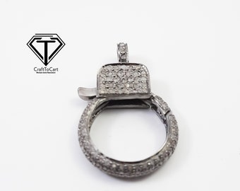 May include: A silver-toned clasp with a round ring and a square top, both encrusted with small white stones.