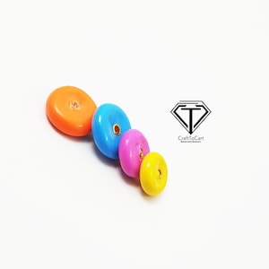 May include: Four colorful round beads with a hole in the center. The beads are orange, blue, pink, and yellow.
