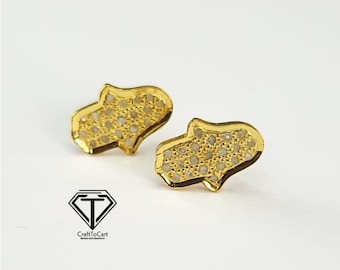 May include: A pair of gold-tone earrings in the shape of a hamsa hand, each with a design of small white stones.
