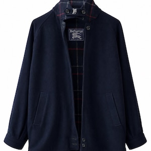 Op de afbeelding: Een marineblauw wollen jasje met een hoge kraag met twee knopen, lange mouwen en twee voorzakken. De binnenvoering heeft een donker ruitpatroon in rood, wit en zwart, met een Burberrys-label voorzien van een logo met een ruiter te paard.