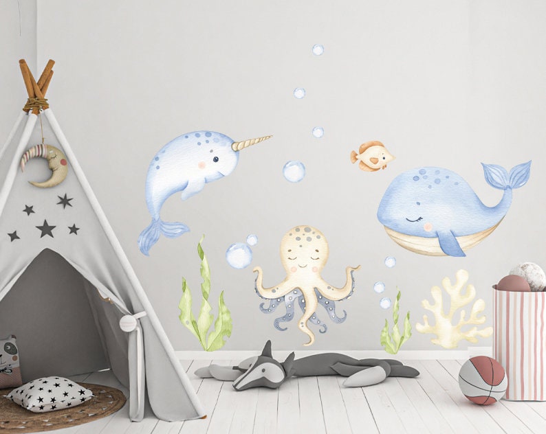 Puede incluir: Un conjunto de calcoman&iacute;as de pared de animales de acuarela azul y beige que incluyen una narval, una ballena, un pulpo y un coral. Las calcoman&iacute;as son perfectas para una guarder&iacute;a o una habitaci&oacute;n infantil.