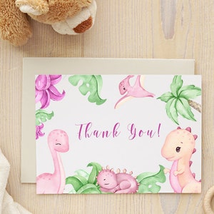 Puede incluir: Tarjeta de agradecimiento acuarela rosa y verde con tem&aacute;tica de dinosaurios. La tarjeta presenta un dinosaurio rosa, una palmera verde y el texto "&iexcl;Gracias!"