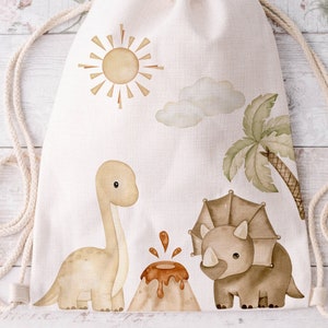 May include: A white drawstring bag with a brown dinosaur, a brown triceratops, a yellow sun, a green palm tree, and a brown volcano on it.