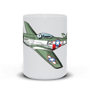 Pode incluir: Uma caneca de cerâmica branca com uma ilustração de desenho animado de um avião de combate P-51 Mustang verde e cinza com marcas vermelhas e brancas. O avião tem uma estrela vermelha e branca na cauda e o texto "E2" no lado.