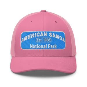 Può includere: Cappellino da camionista rosa con toppa rettangolare blu. La toppa presenta le parole "AMERICAN SAMOA National Park" in lettere bianche, con "Est. 1988" in un carattere più piccolo. Il cappellino ha un retro in rete.