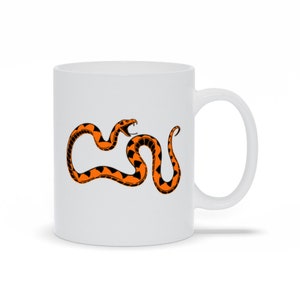 May include: White ceramic mug with a black and orange snake design. The snake is coiled and has its mouth open.