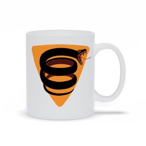 May include: White ceramic mug featuring a black snake coiled within an orange triangle. The snake has a red tongue and is facing the right side of the mug.