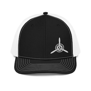 May include: Black and white trucker hat with a white propeller logo embroidered on the front.